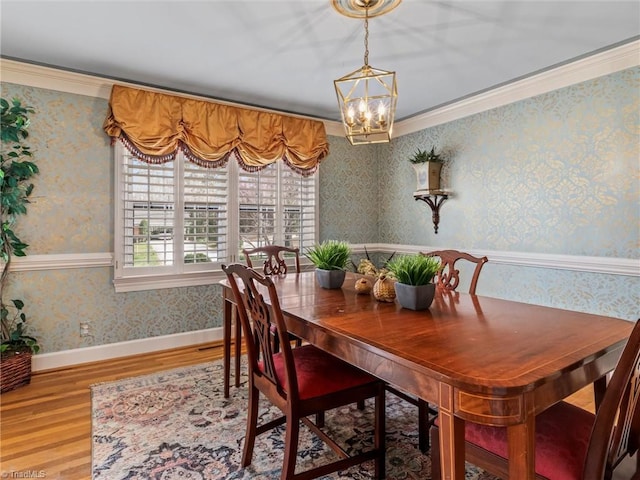 dining room with wood finished floors, baseboards, wallpapered walls, crown molding, and a chandelier