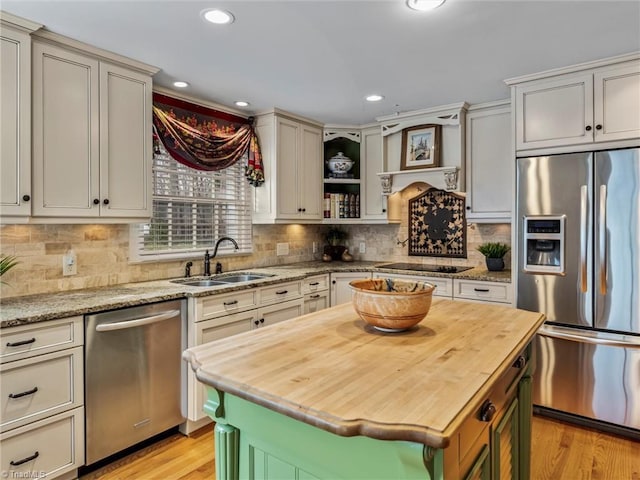 kitchen with a sink, wooden counters, light wood finished floors, and stainless steel appliances