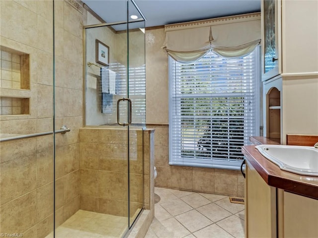 bathroom featuring tile patterned flooring, a shower stall, vanity, and tile walls