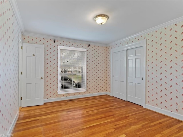 unfurnished bedroom featuring light wood-style floors, crown molding, and wallpapered walls