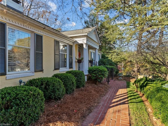 view of property exterior featuring brick siding and a chimney