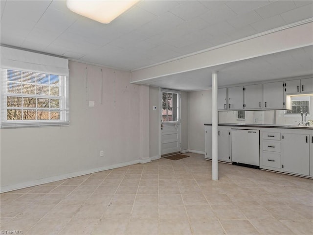 kitchen featuring a sink, baseboards, dark countertops, and white dishwasher