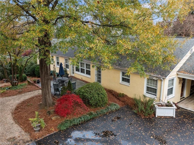 obstructed view of property with brick siding, roof with shingles, and a patio area