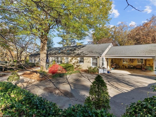 back of house with stucco siding, driveway, a chimney, and roof with shingles