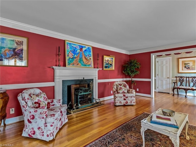 living room featuring a fireplace, crown molding, baseboards, and wood finished floors