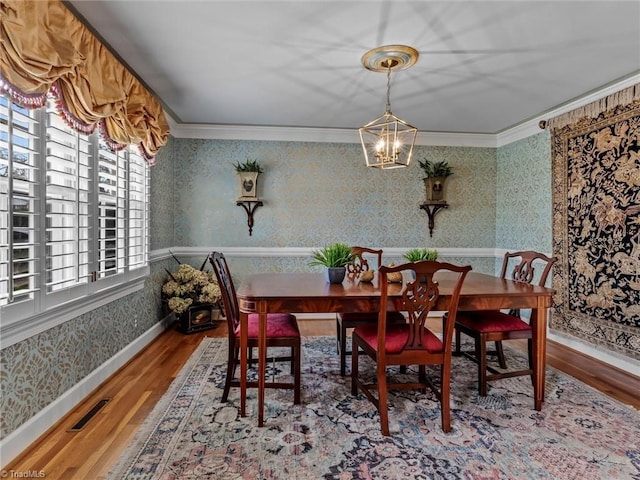 dining room featuring wallpapered walls, crown molding, visible vents, and a chandelier