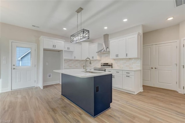 kitchen with wall chimney exhaust hood, white cabinetry, and sink