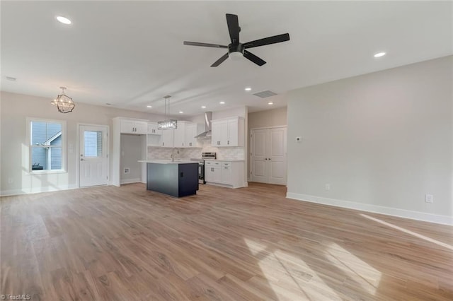 unfurnished living room featuring ceiling fan with notable chandelier, light hardwood / wood-style floors, and sink