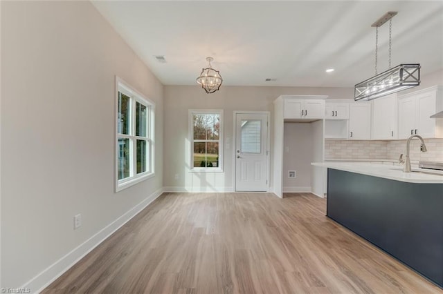 interior space featuring white cabinets, decorative light fixtures, and light hardwood / wood-style floors