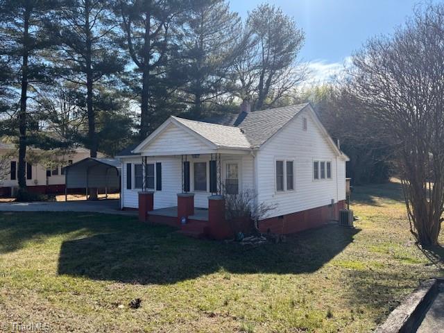 single story home with cooling unit, a front lawn, a carport, and a porch