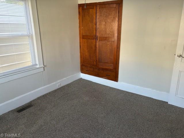 unfurnished bedroom with dark carpet