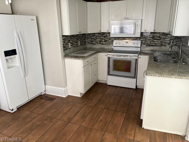 kitchen featuring sink, backsplash, white cabinets, and white appliances