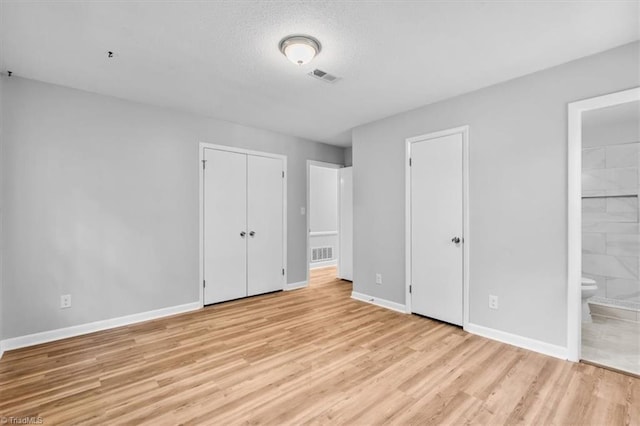4 Manard Ct, Greensboro, NC 27407 - unfurnished bedroom featuring baseboards, light wood finished floors, connected bathroom, and a textured ceiling