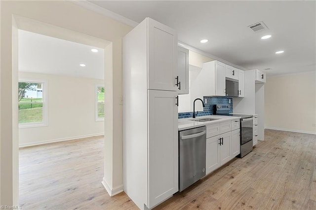 kitchen featuring tasteful backsplash, light wood-style floors, appliances with stainless steel finishes, white cabinets, and a sink