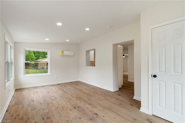 empty room featuring a wall mounted AC, light wood finished floors, recessed lighting, and baseboards