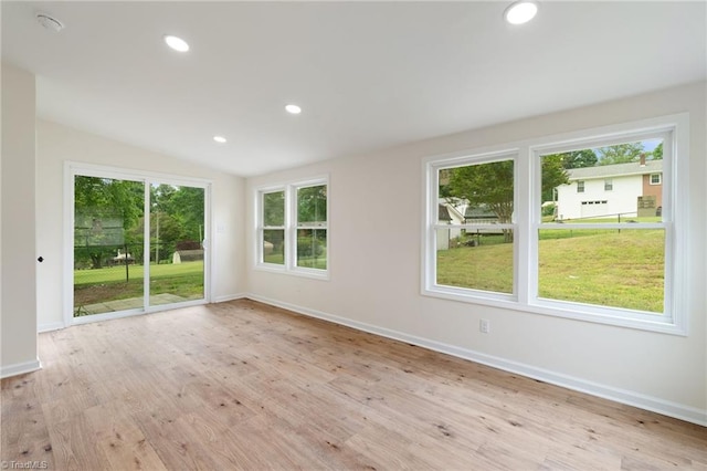 empty room with vaulted ceiling, light wood-style floors, and baseboards