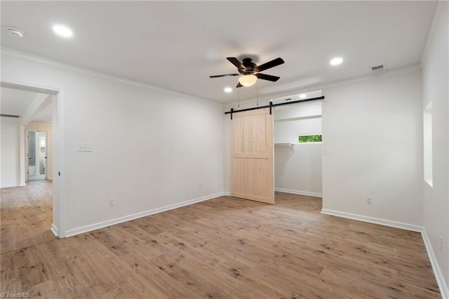unfurnished bedroom with a barn door, crown molding, and baseboards