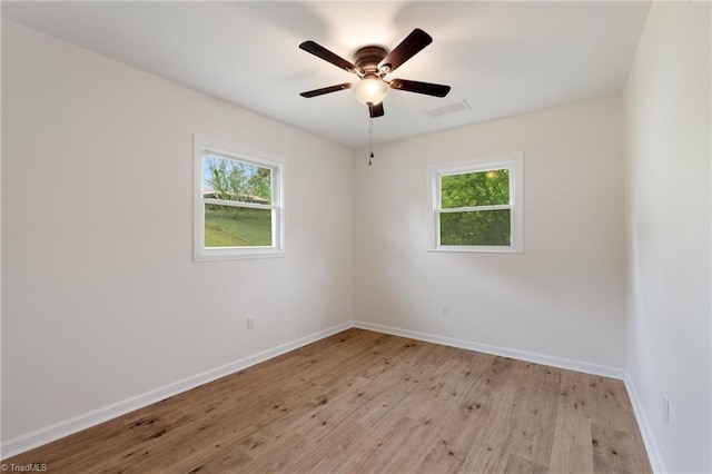 spare room with baseboards, light wood-type flooring, visible vents, and ceiling fan