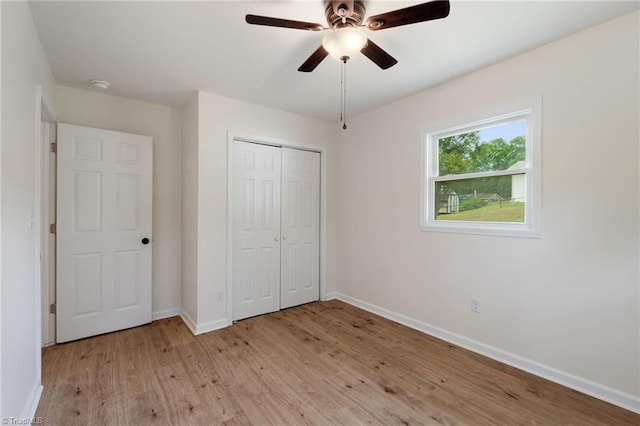 unfurnished bedroom featuring baseboards, a ceiling fan, a closet, and light wood-style flooring