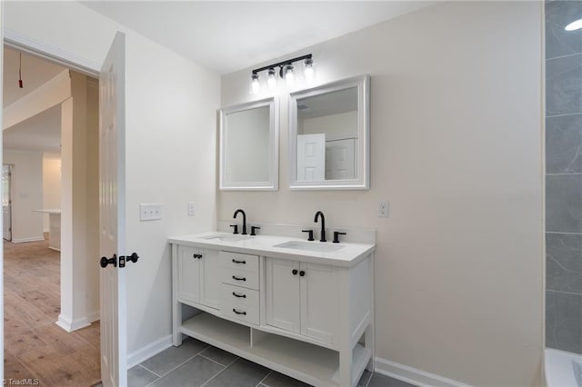 bathroom with double vanity, baseboards, and a sink
