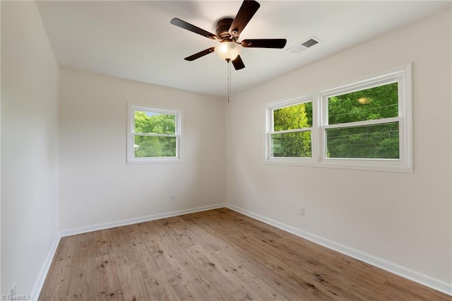 empty room featuring visible vents, a healthy amount of sunlight, light wood-style flooring, and baseboards