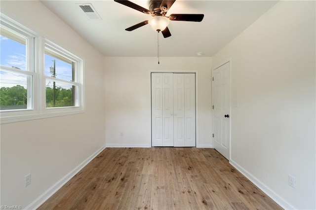 unfurnished bedroom featuring a closet, visible vents, hardwood / wood-style flooring, and baseboards