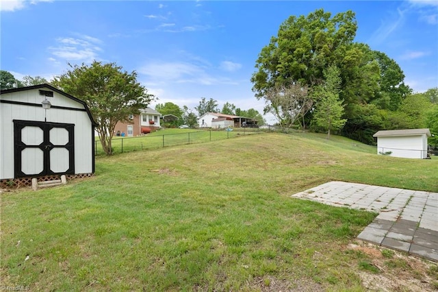view of yard with fence, an outdoor structure, a patio area, and a shed