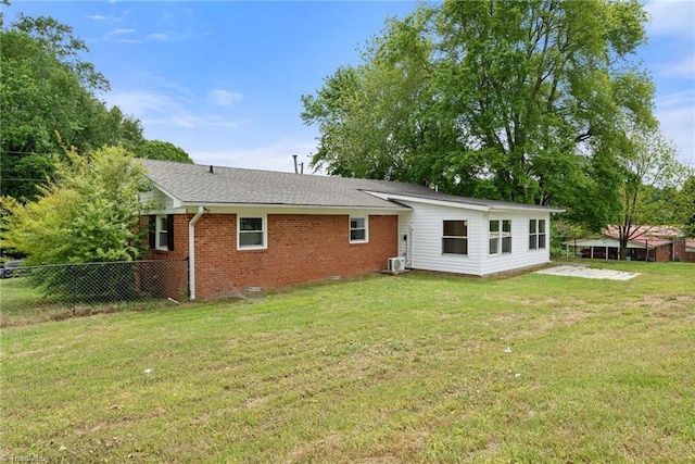 rear view of property with a yard, brick siding, fence, a shingled roof, and central AC