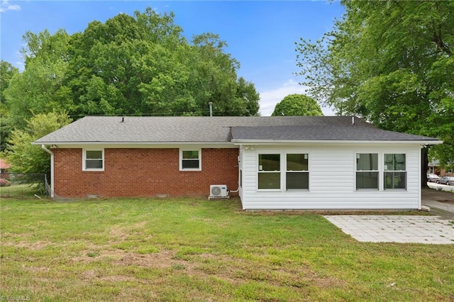 back of house with brick siding, fence, a patio, roof with shingles, and a lawn
