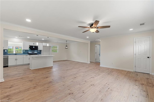 unfurnished living room featuring light wood-type flooring, ornamental molding, a ceiling fan, and a sink