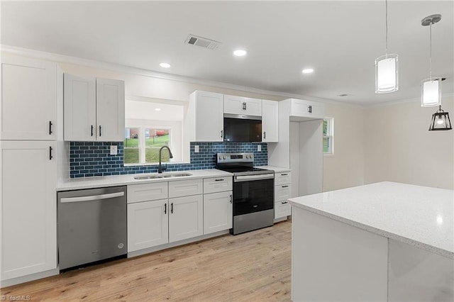 kitchen with appliances with stainless steel finishes, backsplash, a sink, light wood-type flooring, and crown molding