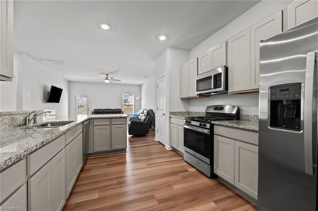 kitchen featuring open floor plan, ceiling fan, recessed lighting, a sink, and stainless steel appliances