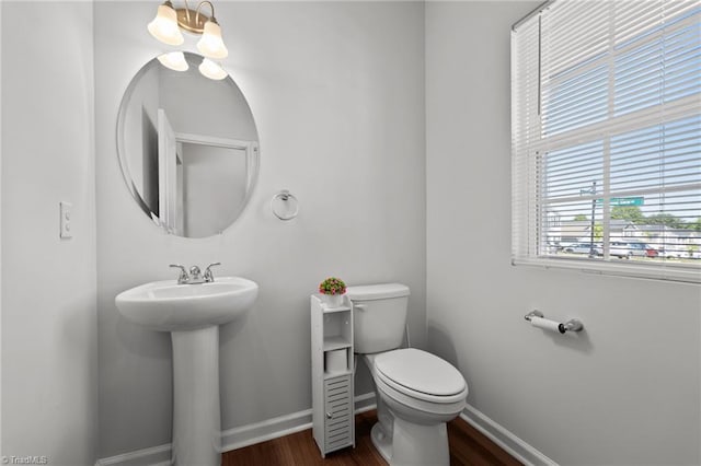 half bathroom with toilet, baseboards, and wood finished floors