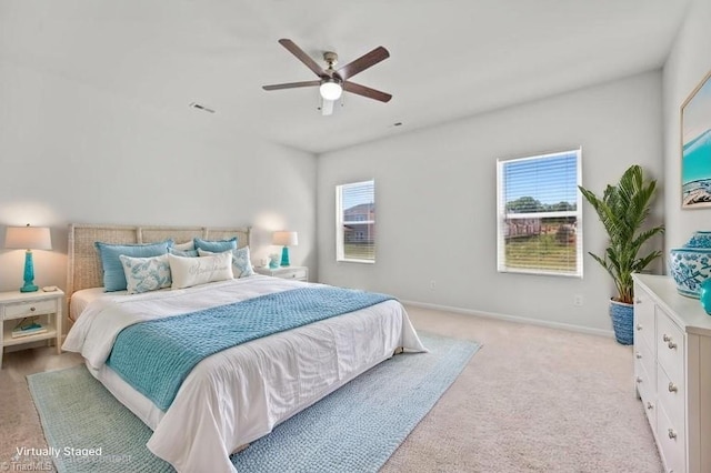bedroom with a ceiling fan, baseboards, multiple windows, and light carpet