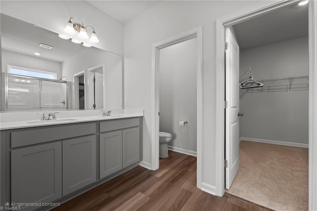 bathroom featuring a sink, toilet, wood finished floors, and a spacious closet
