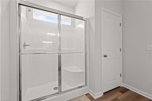 bathroom with baseboards, a shower stall, and wood finished floors