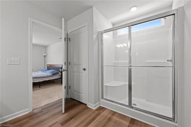 bathroom with baseboards, a shower stall, ensuite bath, and wood finished floors