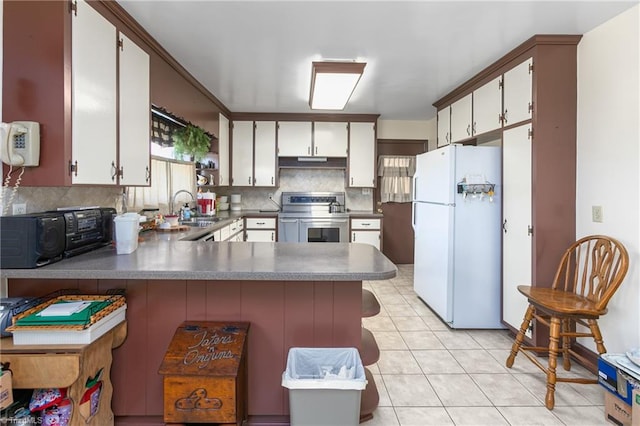 kitchen featuring stainless steel electric range, backsplash, kitchen peninsula, sink, and white refrigerator