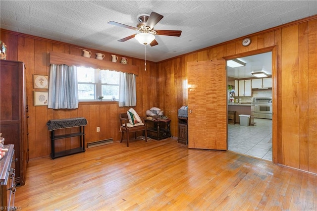 office area with light hardwood / wood-style flooring, a baseboard radiator, ceiling fan, and wooden walls