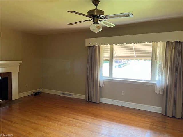 unfurnished living room with light wood-type flooring, ceiling fan, and a brick fireplace