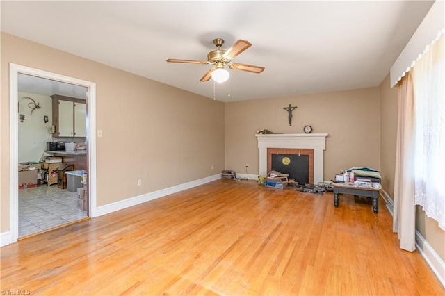 living room featuring ceiling fan, light wood-type flooring, and a fireplace