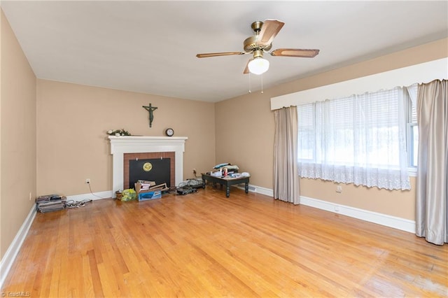 unfurnished living room with light wood-type flooring, a brick fireplace, and ceiling fan