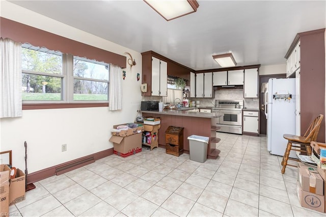 kitchen with stainless steel range with electric stovetop, white fridge, tasteful backsplash, kitchen peninsula, and sink