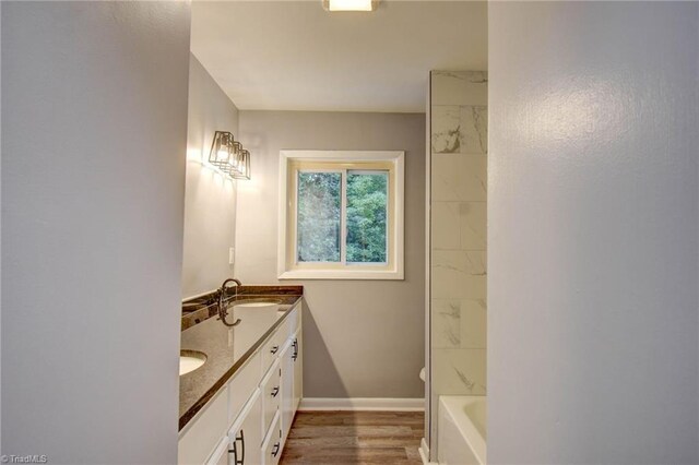 bathroom with wood-type flooring, toilet, vanity, and a washtub