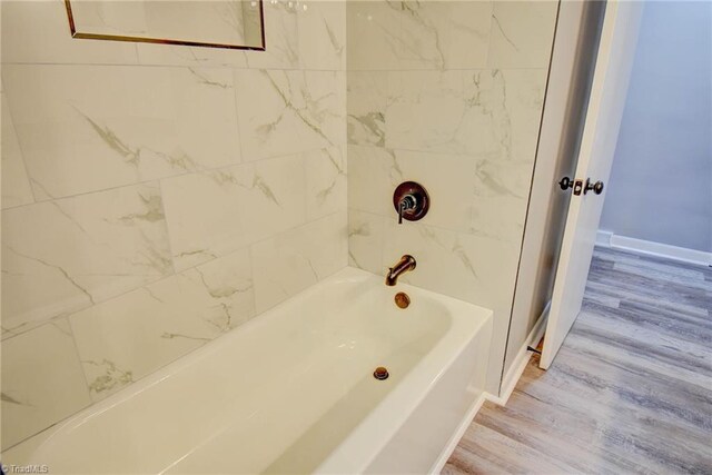 bathroom with hardwood / wood-style flooring and tiled shower / bath