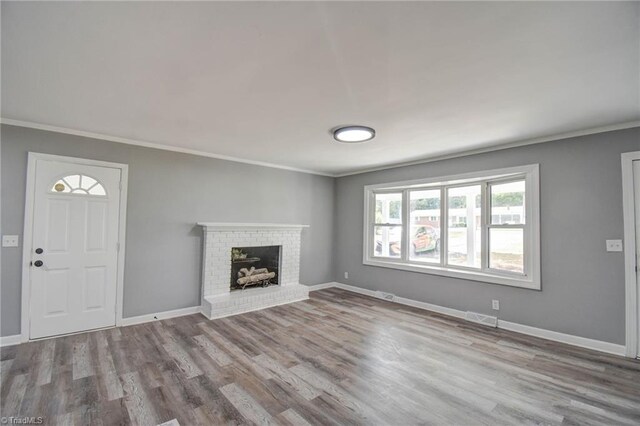 unfurnished living room featuring ornamental molding, a brick fireplace, and light hardwood / wood-style floors