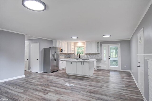 kitchen with light wood-type flooring, a kitchen island, stainless steel appliances, and white cabinetry