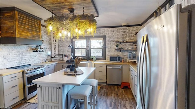 kitchen featuring stainless steel appliances, a kitchen island, brick wall, and dark hardwood / wood-style floors