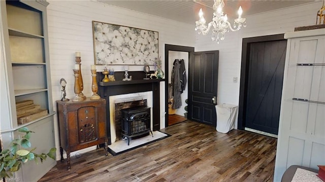 interior space featuring built in shelves, dark wood-type flooring, an inviting chandelier, and a wood stove