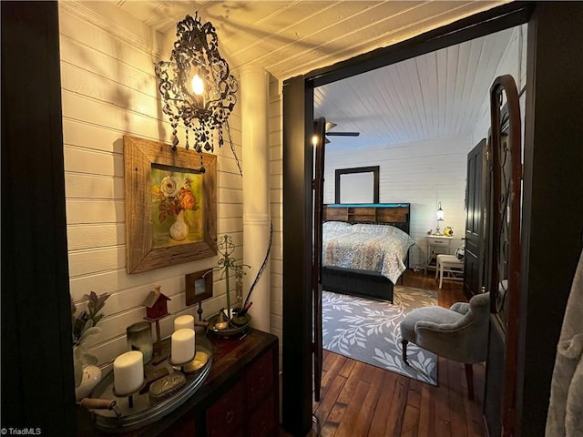 bedroom with dark wood-type flooring and wood walls